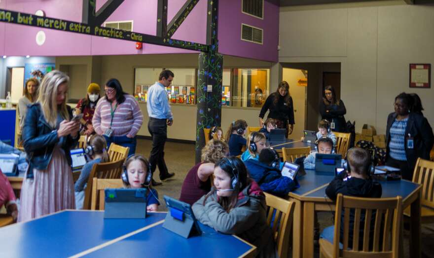 Adults mill around as students participate in virtual tutoring sessions at Durham Elementary in Tigard, Ore., on Nov. 7, 2022. Durham is one of several schools in the country piloting the Ignite! Reading program, which utilizes one-on-one tutoring to help students with reading skills.