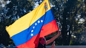 A woman waves Venezuela's flag out her car sunroof in celebration 
