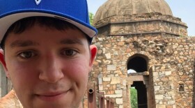 Aaron Michael looks at the camera, a stone tower behind him,