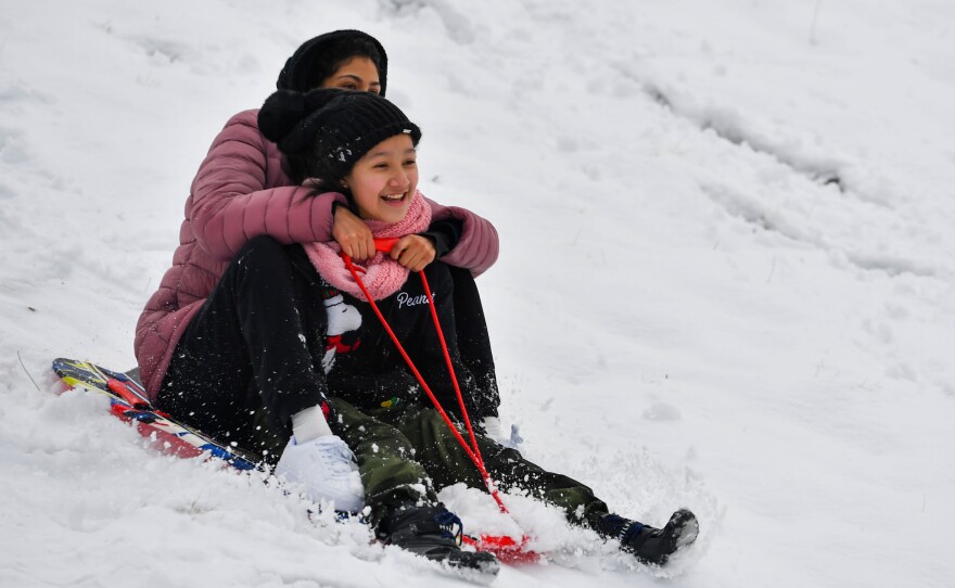Valentine Flores, 10, and her sister-in-law, Elianny Hernandez, slide down the hill at Kirby Park.