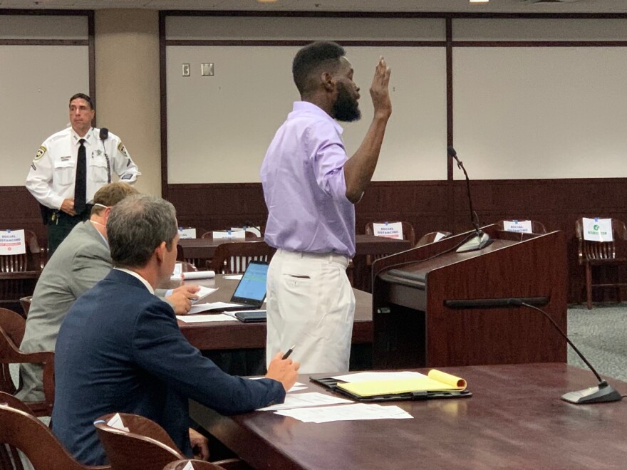 man at courtroom podium takes oath 