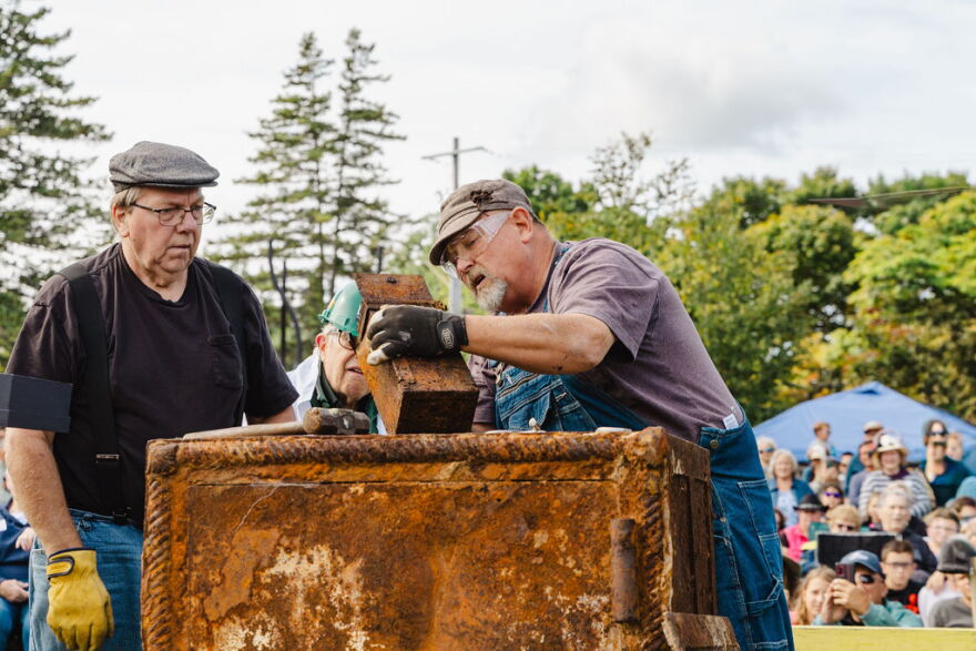 Three men look inside of the a rusted metal box that was removed from a thousand-pound, century-old, safe. 