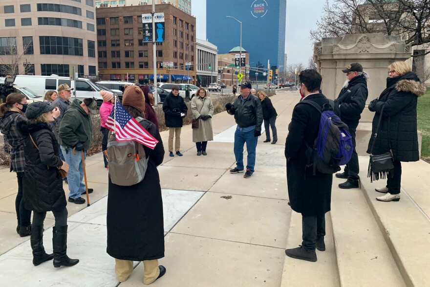 A small of protesters gather outside the Statehouse to back a measure that would immediately cancel the governor's public health emergency declaration.