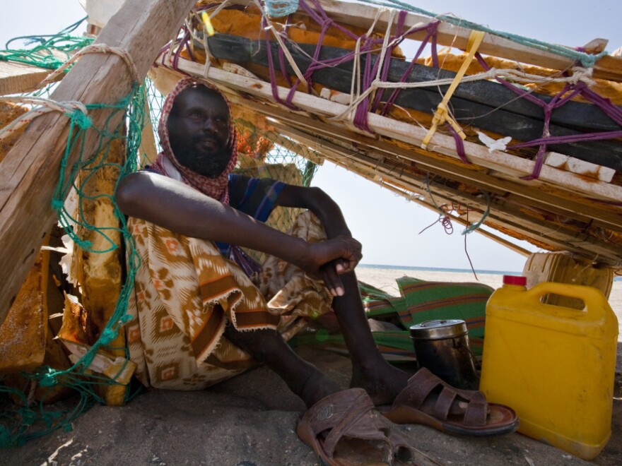 Suleman Ahmen Aden shades himself beneath his fishing raft. Last year, he helped catch pirates who were forced to beach their boat because of a disabled engine.
