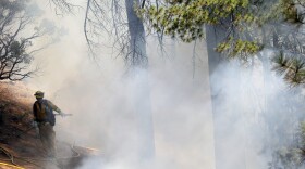 A firefighter is surrounded by smoke while fighting the King Fire on Tuesday, Sept. 23, 2014, in Mosquito, Calif. Nearly 2,000 firefighters were added Tuesday to battle a massive Northern California wildfire threatening thousands of homes in anticipation of erratic winds and hotter temperatures that could undo their progress.