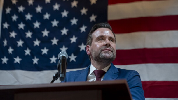 Josh Turek appears at a podium, in front of an American flag.