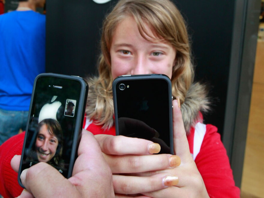 Emilie Weideman and her father, Marc Weideman try their new iPhones Thursday in Palo Alto, Calif. Many of the new phones' owners are complaining of a glitch that drops calls.