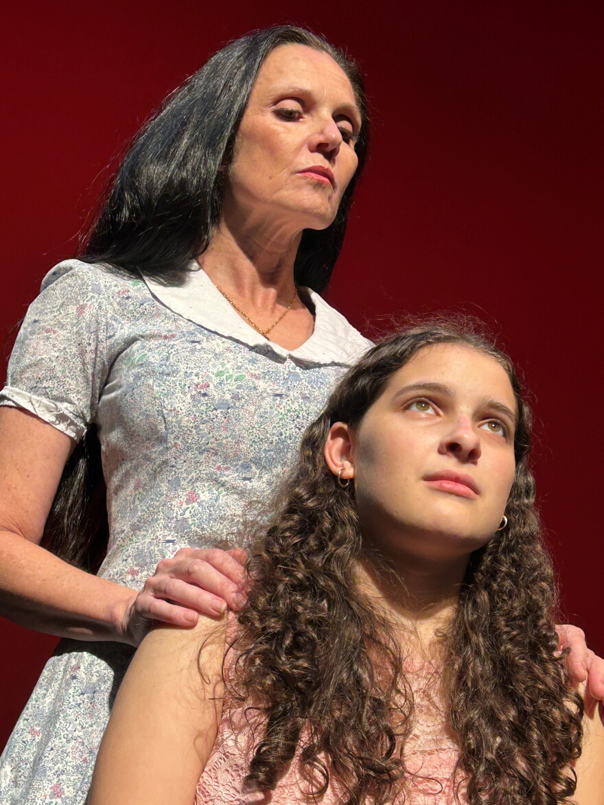Woman playing a mother looking mean stares down at her fake daughter holding her shoulders 