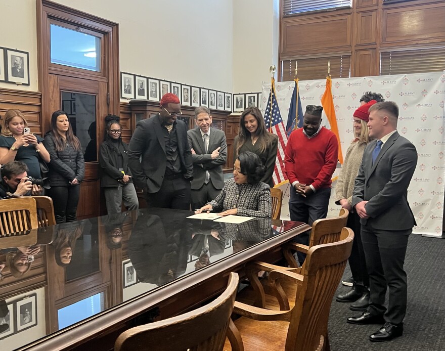 Mayor Applyrs signing an executive order on Jan. 2, with Albany business owners behind her