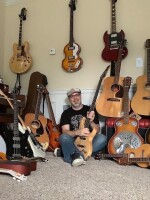 Lee Dellapina surrounded by more than a dozen guitars.