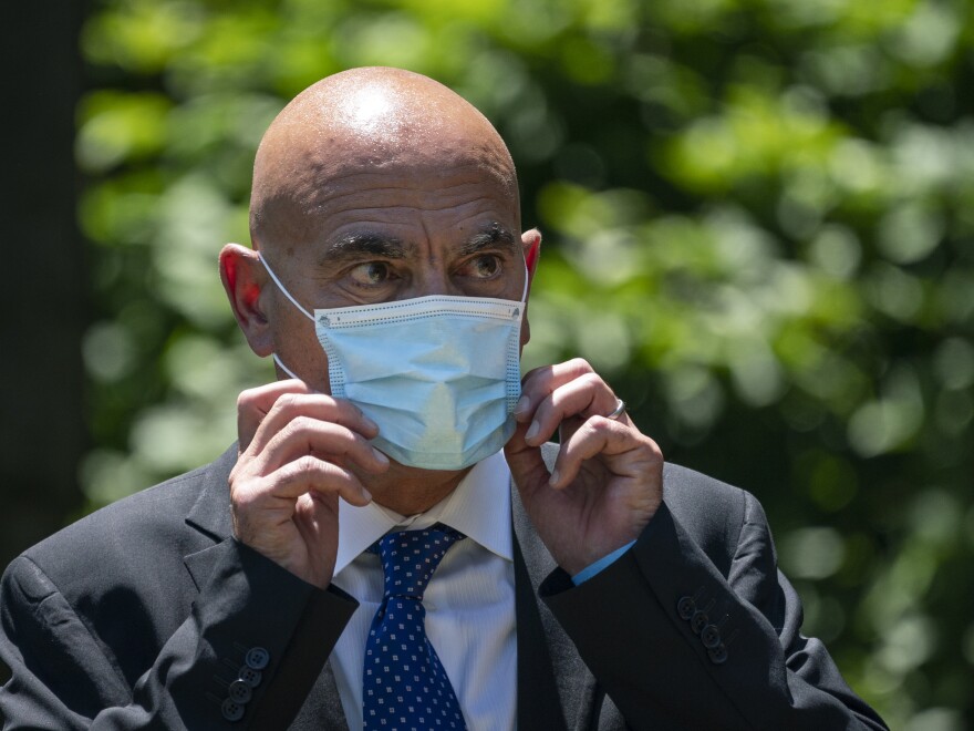 Moncef Slaoui, chief scientific adviser for Operation Warp Speed, listens as President Trump delivers remarks about coronavirus vaccine development in the Rose Garden on May 15. Slaoui says Americans could start seeing a vaccine by the middle of December.