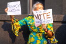 A protester holds up anti-Flock placades outside Richmond City Hall during a demonstration against Flock cameras before a City Council meeting on July 27, 2026.