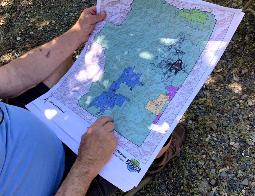 John Maupin holds a map showing the current fire districts in Josephine County with the unincorporated area in green.