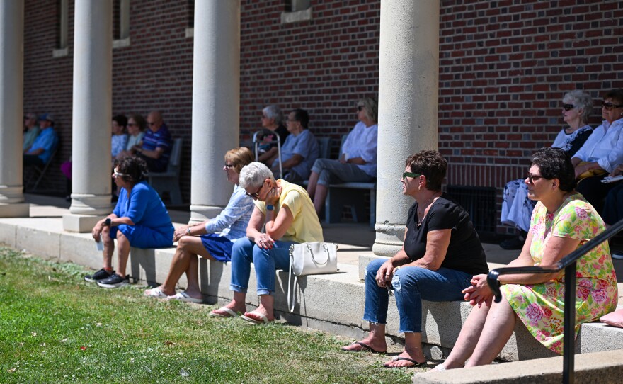 Parishioners sit outside St. Ann's Basilica for Mass on Monday.