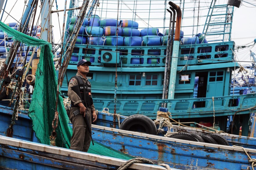 A police officer inspects a fishing boat in Thailand.