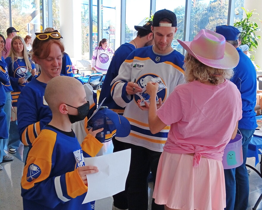 Buffalo Sabres forward Josh Norris sign an autograph for a young fan while Jared, at left front, waits his turn with his mother Amanda at his side. Norris and other Sabres players visited Roswell Park Comprehensive Cancer Institute Monday, Oct. 19, 2026.
