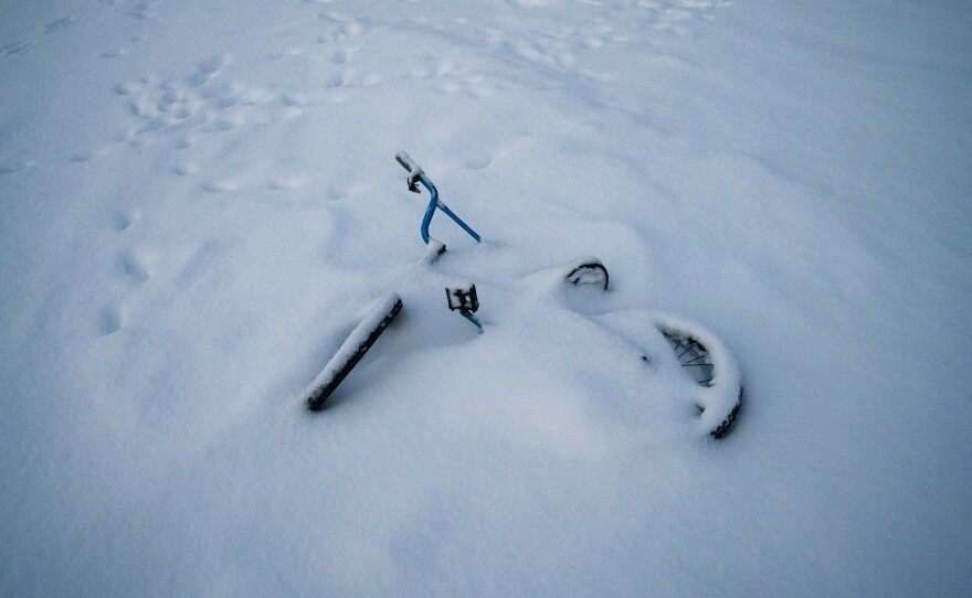 A children's bicycle lays in snow from a recent winter storm.