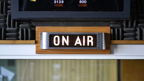 An "on air" sign is lit up in a radio studio.