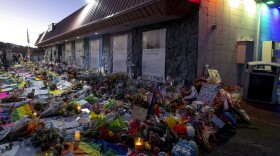 Mourners gather outside Club Q to visit a memorial, which has been moved from a sidewalk outside of police tape that was surrounding the club, on Friday, Nov. 25, 2022, in Colorado Spring, Colo.