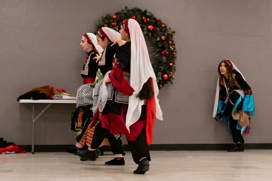 Zeina Diab (right) adjusts her shoe as she observes fellow dancers practice at First St. Charles United Methodist Church ahead of Canaan Wellspring Dabke Dance Troupe’s performance on Saturday.