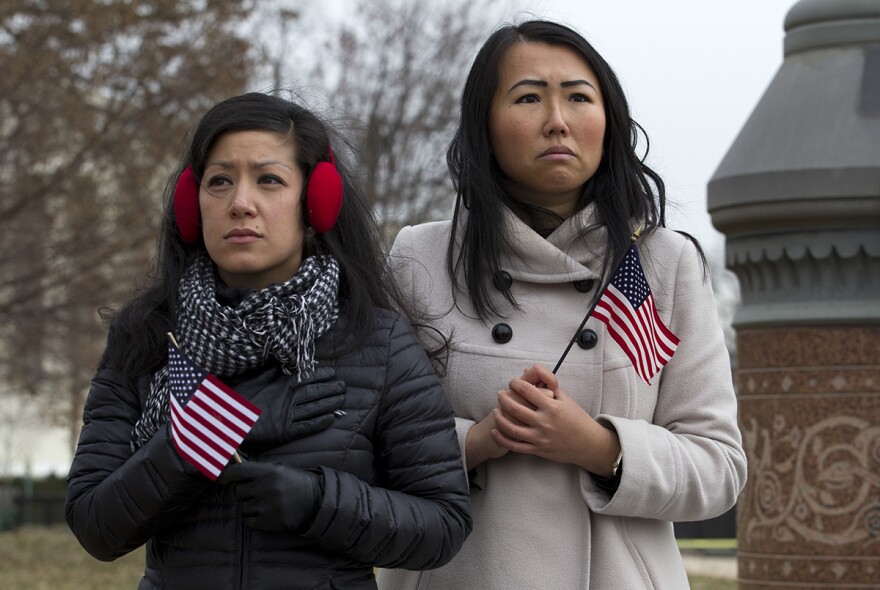 Stephanie Penn, left, and Tiffany Ge watch the flag-draped casket of former President George H. W. Bush carried by a joint services military honor guard down the steps of the U.S. Capitol, Wednesday, Dec. 5, 2018, in Washington. 