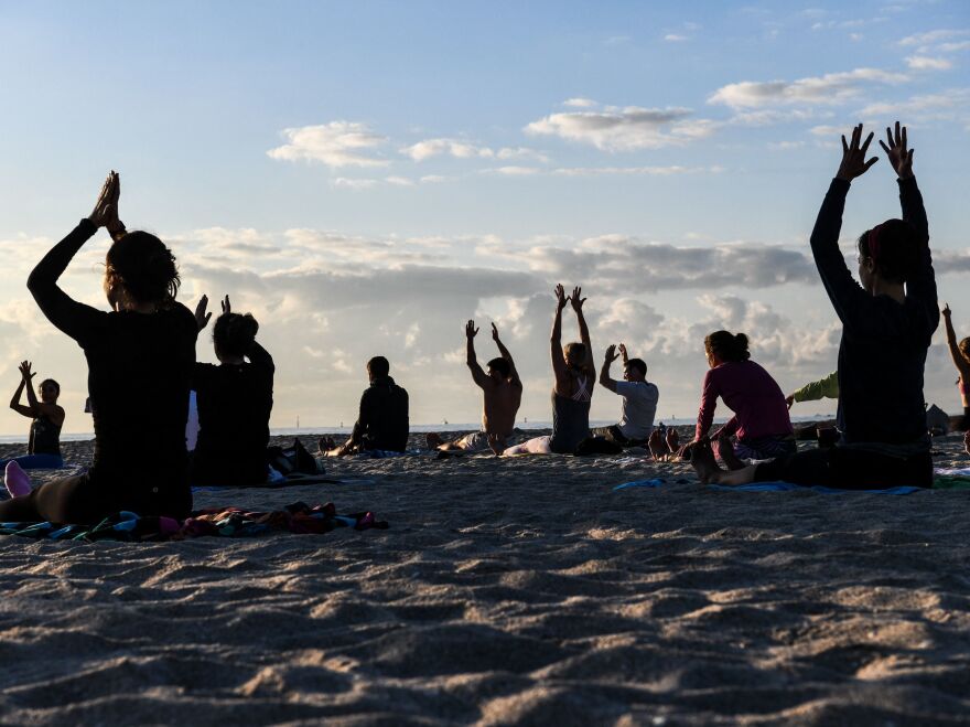 A group of people participate in a yoga session on the beach in Miami Beach, Fla., on March 23, 2021.