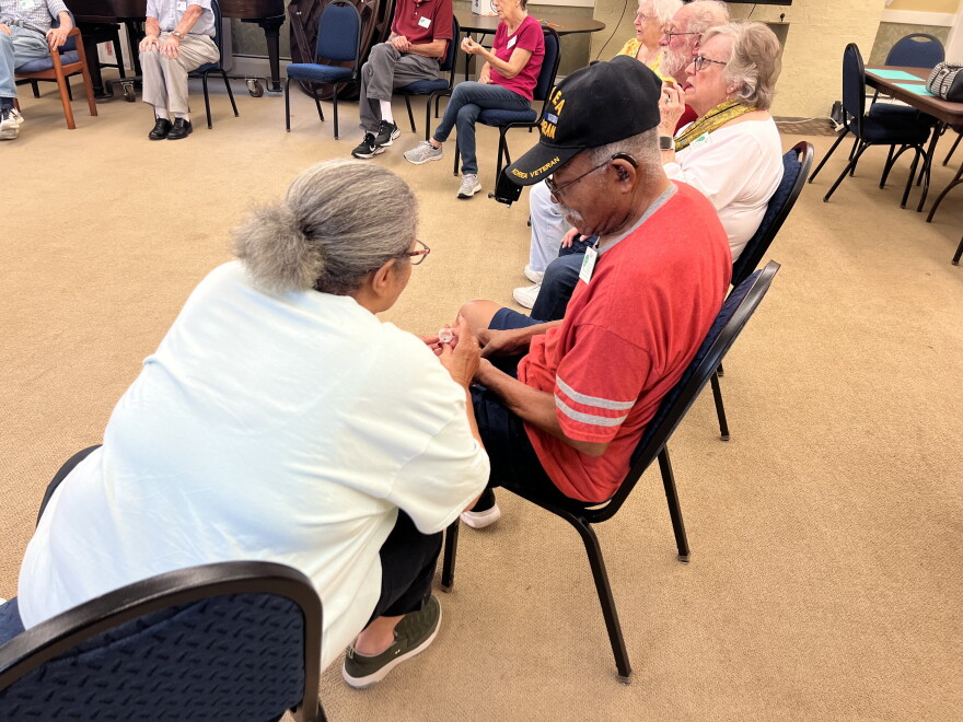 Memory cafe participants peer at a shark tooth that a community member brought in for the beach-themed session.