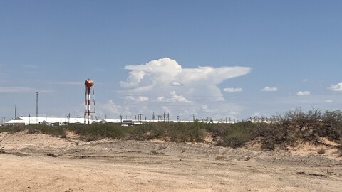 The tops of large white tents are visible in the desert area at Fort Bliss. ICE erected the massive immigration detention camp to house hundreds of people as part of the Trump administration's mass deportation effort. The facility on military land is run by a private contractor.