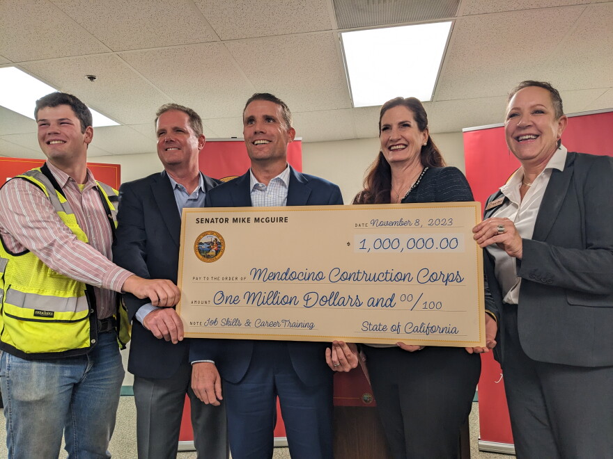 People holding a giant mock-up a million-dollar check from the state to Mendocino Construction Corps.