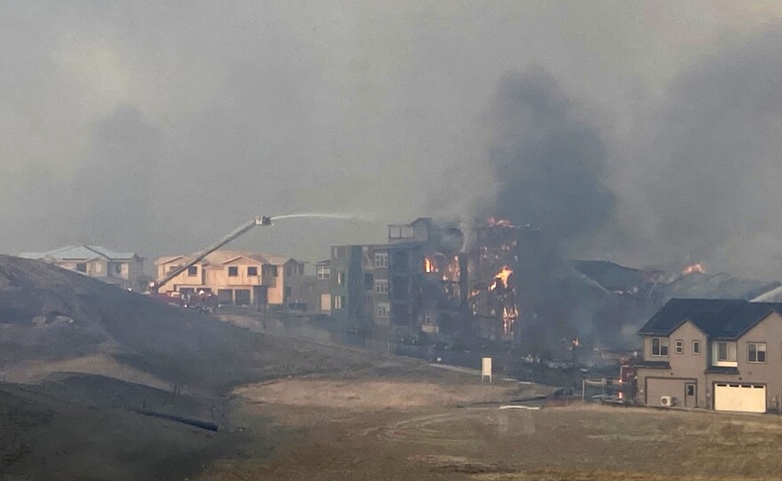 Firefighters spray water on a structure fire as a wildfire burns on Dec. 30, 2021 in Superior, Colorado. Thousands of residents in Superior and Louisville were ordered to evacuate Thursday because of a wind-fueled wildfire that engulfed parts of the area in smoky, orangish skies.