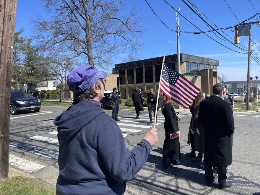 A woman watches with an American flag as the funeral procession drives by. "It's the least I can do," she said.