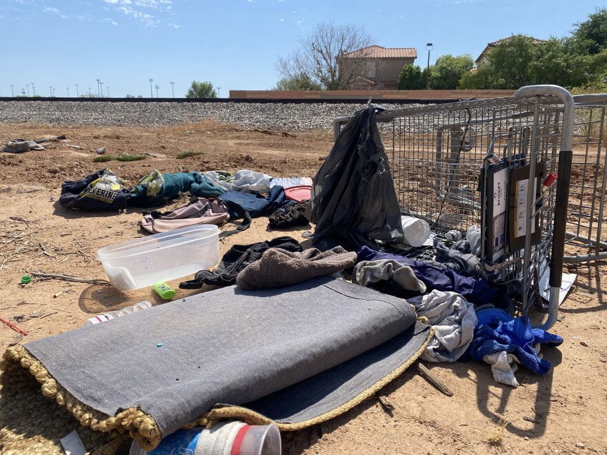 Shopping cart with items littered across the sand next to train tracks in Chandler, Ariz. 