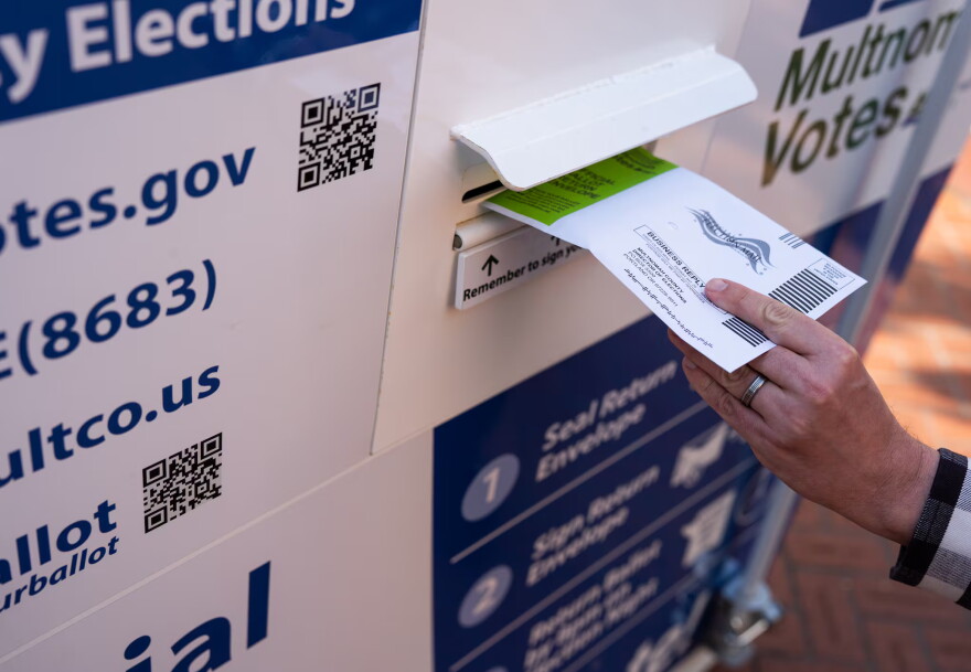 A voter drops off their ballot at a Multnomah County ballot drop box in Pioneer Courthouse Square in May 2026.