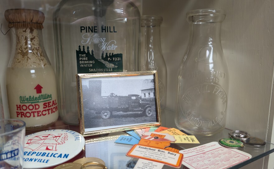 Glass bottles, a black and white photograph, and knick knacks on a glass shelf