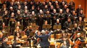 A man in a blue blazer conducts an orchestra