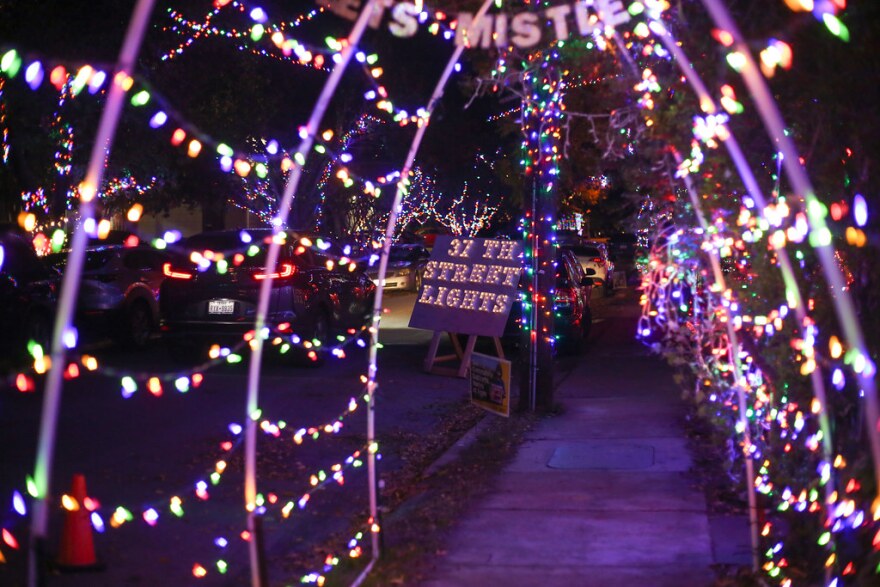 A tunnel of holiday lights, leading to a lit-up sign that says, "37th Street Lights."