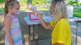 A woman takes a child's temperature