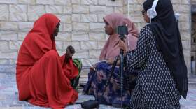 Two female journalists working for Bilan Media, a Somali start-up staffed entirely by women, interview a woman running a restaurant in a market in Mogadishu on May 22, 2022. (Hasan Ali Elmi/AFP via Getty Images)