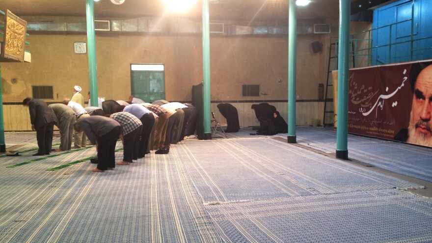 Khomeini, the former supreme leader, watches over pilgrims praying at the <em>husseiniya</em>, or Shiite place of worship, where he used to preach.