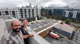 People standing atop a brewery roof overlooking solar panels