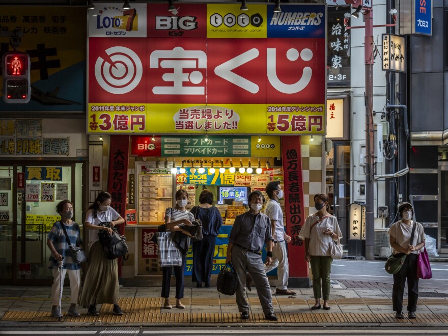 TOKYO, JAPAN - JULY 28: People wearing face masks wait to cross a street on July 28, 2021 in Tokyo, Japan. Tokyo metropolitan government reported 3,177 new coronavirus cases on Tuesday, an increase on yesterday and the highest number of infections recorded so far for the city. As the Olympics gets fully underway, concern continues to linger around the safety of holding such a large event during the global Covid-19 pandemic. (Photo by Yuichi Yamazaki/Getty Images)