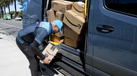 A driver picks up a package while making deliveries for Amazon in Costa Mesa, Calif., on March 23. Amazon is offering to permanent jobs for 125,000 workers it hired to deal with a sharp rise in online shopping during the coronavirus pandemic.