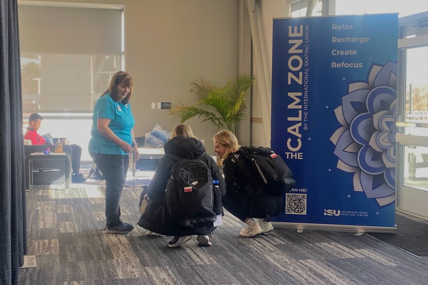 Two athletes meet a therapy dog in the Calm Zone at the ISU World Cup Speed Skating competition at the Utah Olympic Oval in Kearns, Nov. 15, 2025.