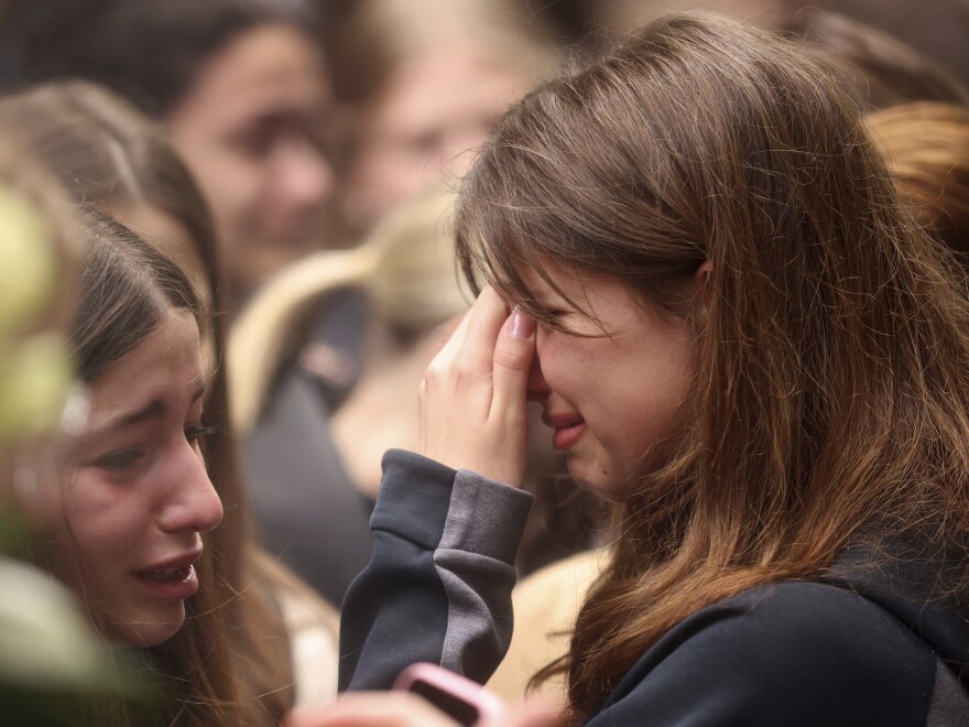 A woman cries as people light candles for the victims near the Vladislav Ribnikar school in Belgrade, Serbia, Thursday, May 4, 2023.