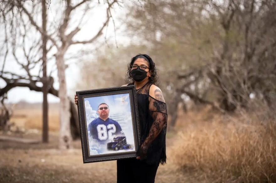 Ana Flores Arguelles stands outside holding a framed photo of her husband Andres Arguelles.