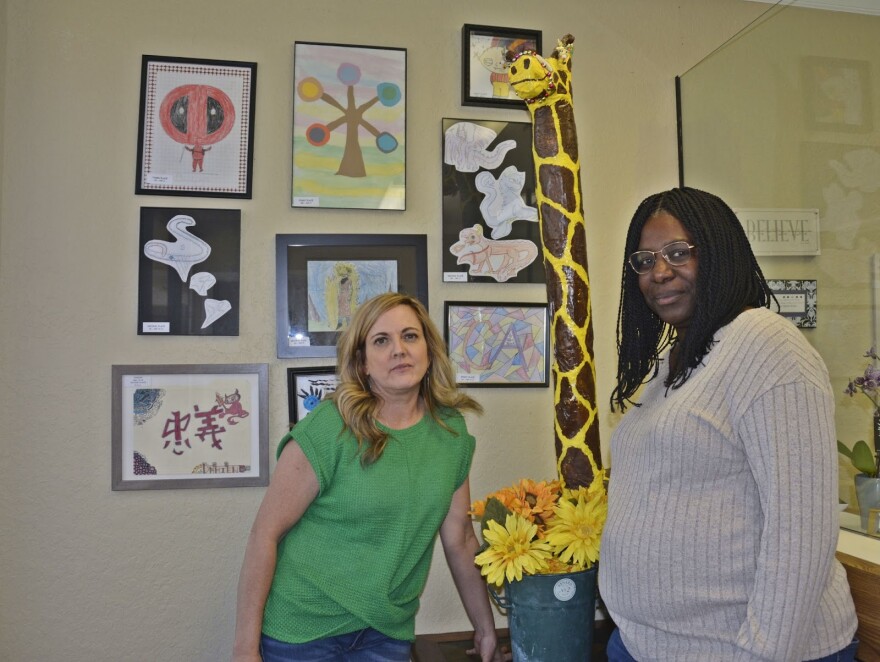 Angie Beringer (left) and Lisa Jacobs of Creative Alternatives pose with artwork done by foster youth in their Turlock office.