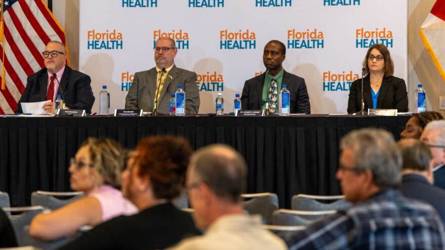 Kent Donahue. public information officer at the Florida Department of Health in Orange County, from left, Tom Bendle with the department's Division of Disease Control, and Surgeon General Dr. Joseph Ladapo list to a speaker during Thursday's hearing on school immunization requirements, in Lake Mary on Oct. 9, 2026.