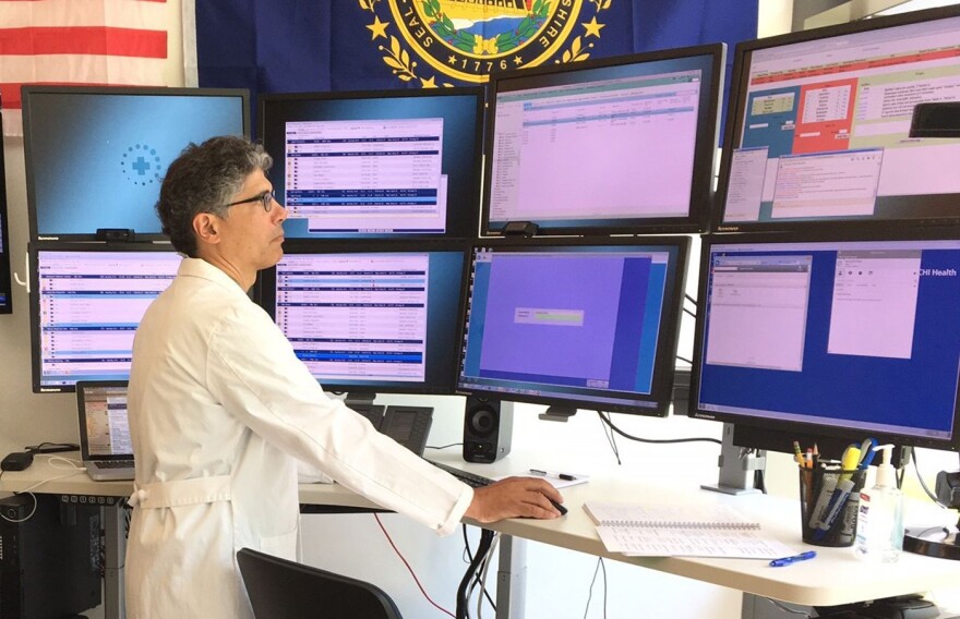 Dr. Athos Rassias stands in front of computer screens at Dartmouth-Hitchcock Medical Center