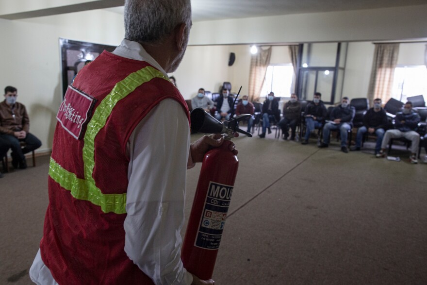 Ali Moussa, 60, teaches a fire-fighting course to a room full of volunteers in the town of Mishmish.