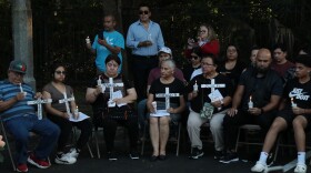 Attendees at a vigil Wednesday, May 15, 2024, hold white crosses with the names of those who died in the bus accident on Tuesday.